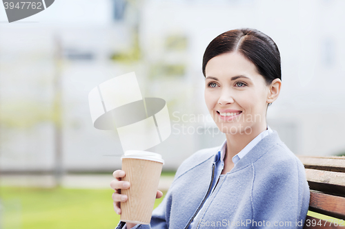 Image of smiling woman drinking coffee outdoors