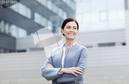 Image of young smiling businesswoman over office building