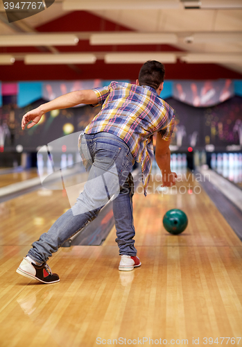 Image of happy young man throwing ball in bowling club