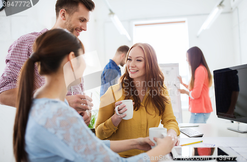 Image of happy creative team drinking coffee at office