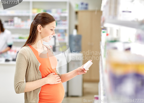 Image of happy pregnant woman with medication at pharmacy