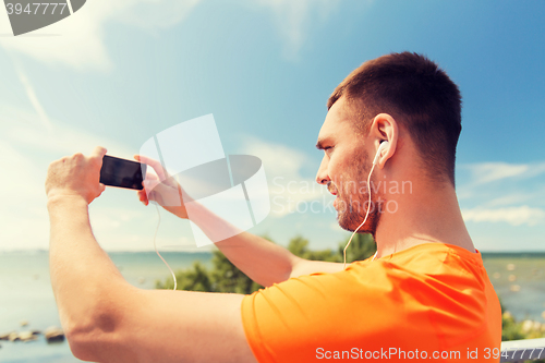 Image of smiling young man with smartphone and earphones