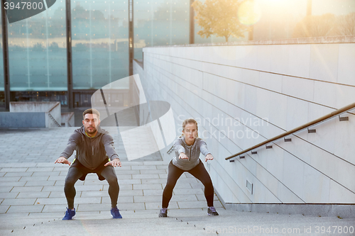 Image of couple doing squats on city street stairs