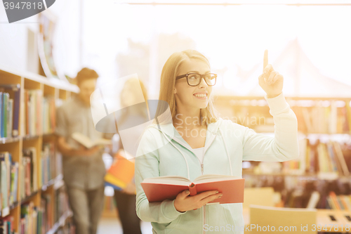 Image of happy student girl or woman with book in library