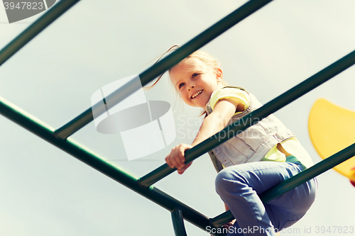 Image of happy little girl climbing on children playground