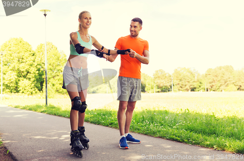 Image of happy couple with roller skates riding outdoors