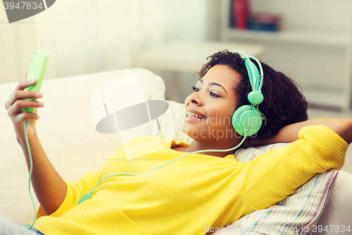 Image of happy african woman with smartphone and headphones