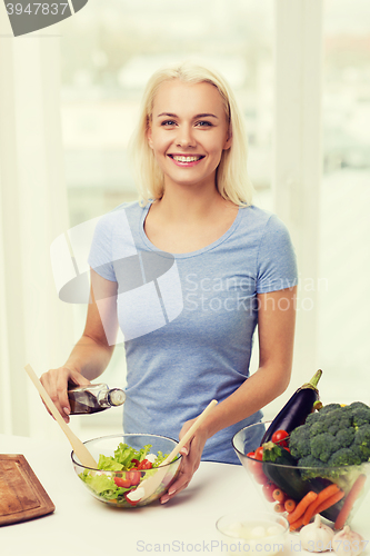 Image of smiling woman cooking vegetable salad at home