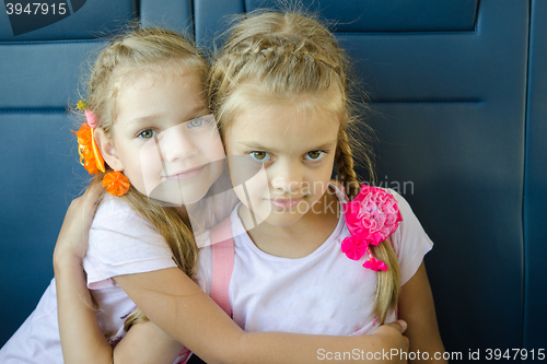 Image of Two girls hugging look in the frame, sitting in an electric train, close-up