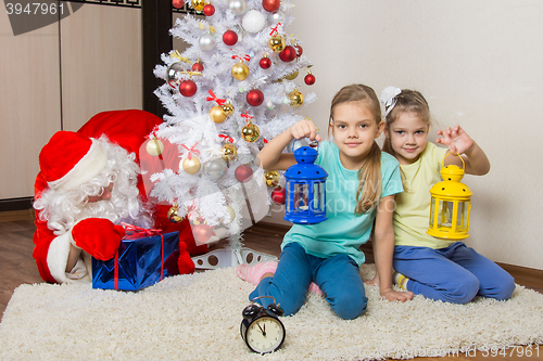 Image of Two girls with flashlights waiting for Santa Claus at the Christmas tree in New Years Eve