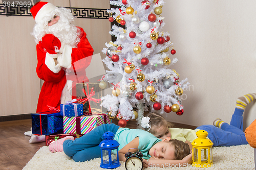 Image of Santa Claus brought gifts for New Years Eve and softened faces of the two sleeping sisters
