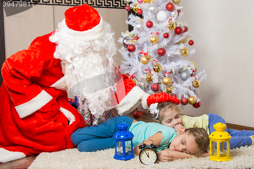 Image of Santa Claus brought gifts and pats on the head of sleeping children