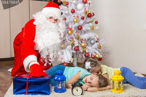 Image of Santa Claus in New Years Eve puts the gift in front of sleeping sister