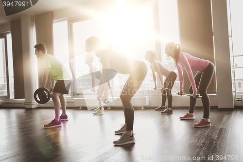 Image of group of people exercising with barbell in gym