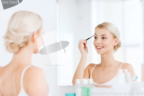 Image of woman with brush doing eyebrow makeup at bathroom