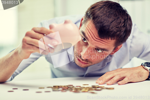 Image of businessman with piggy bank and coins at office