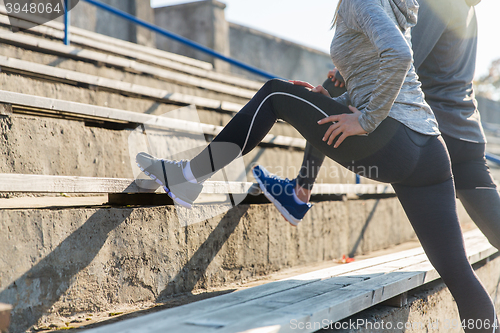 Image of close up of couple stretching leg on stadium