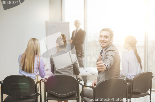 Image of businessman with team showing thumbs up in office