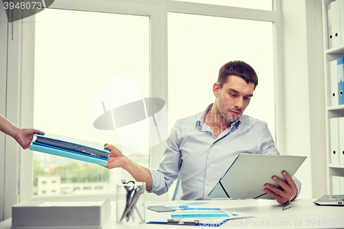 Image of businessman taking papers from secretary in office