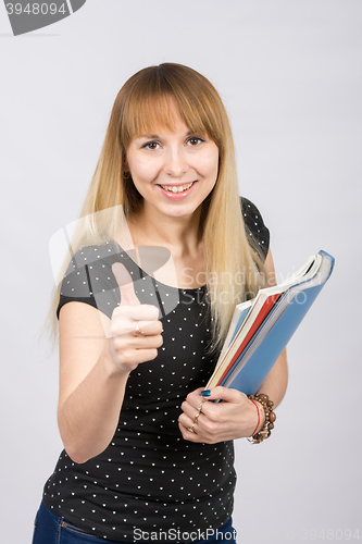 Image of Young woman with folders in hands happily smiling and showing thumb