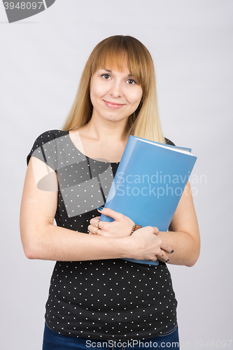 Image of The girl is with a smile and holds folder with documents to his chest