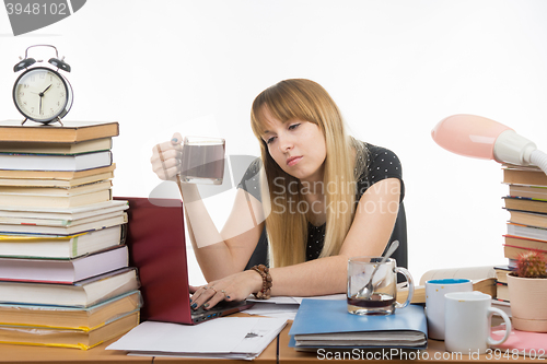 Image of Student falls asleep with a mug of coffee in hand, working in a laptop