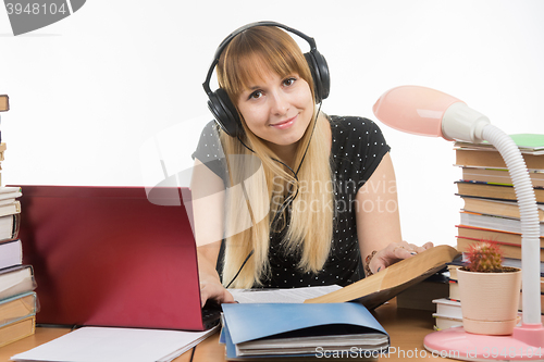 Image of Happy student with headphones preparing for exams at the table looked at the frame