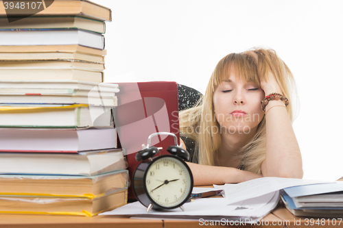 Image of Student fell asleep leaning his head on his hand, late at night in preparation for the exam