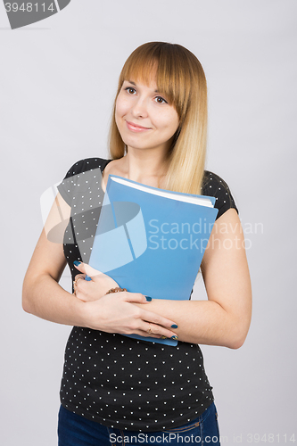 Image of Girl with a dreamy look standing with folders in hands
