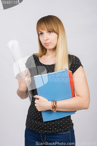 Image of Young girl with folders and a roll of paper in the hands of a sad looking forward