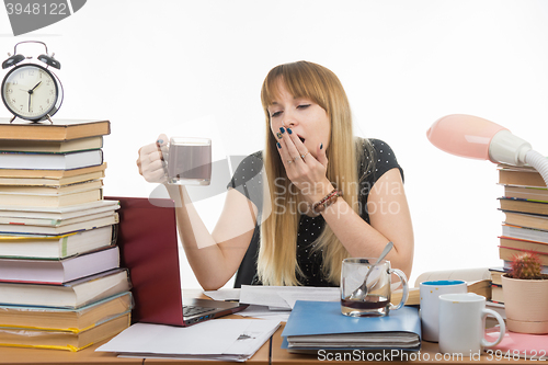 Image of Girl student doing night yawns, holding another cup of coffee hands