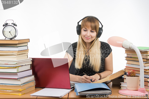 Image of Student with headphones ready to pass the diploma project is looking for information on the Internet