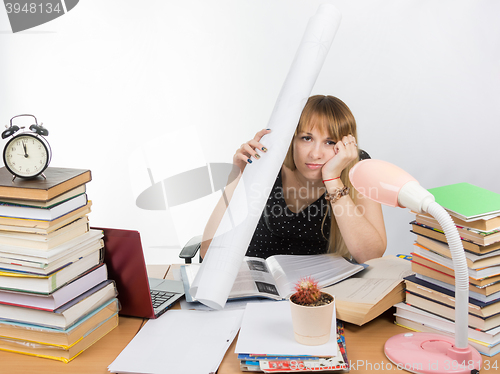 Image of Tired student sitting at the table and put a figure to the head