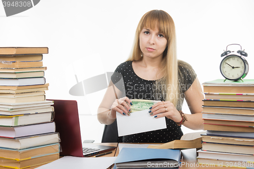 Image of Upset girl student puts money in an envelope to bribe the teacher in the exam