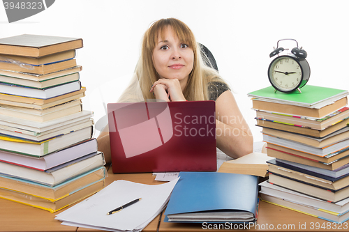 Image of Disheveled student sitting at the table and looking at the frame