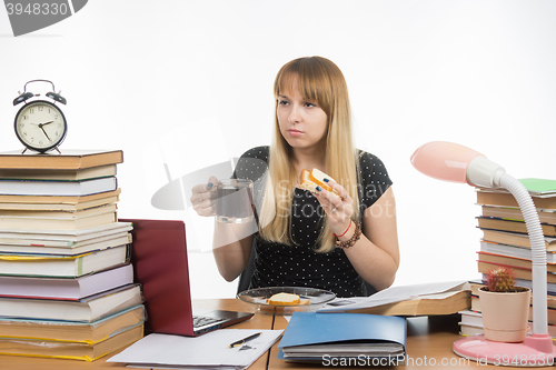 Image of Hungry young teacher sitting wearily with a sandwich and coffee