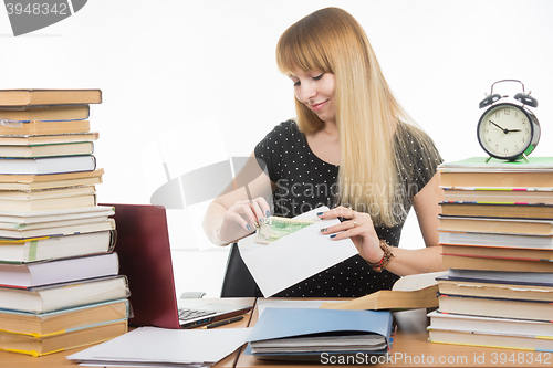 Image of The girl puts money in an envelope to bribe the teacher in the exam