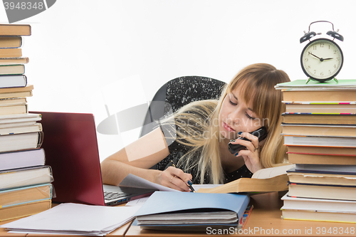 Image of Student talking on the phone writing something on a piece of paper