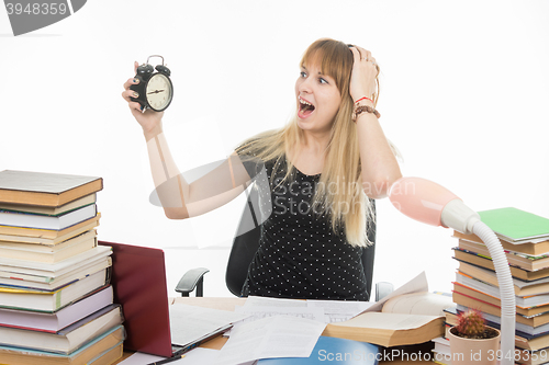 Image of A student with an alarm clock in hands understand that slept exam and screaming looking at his watch