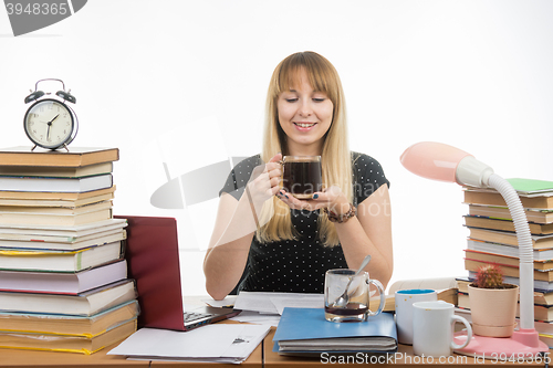 Image of Girl student happily looks at a glass of coffee