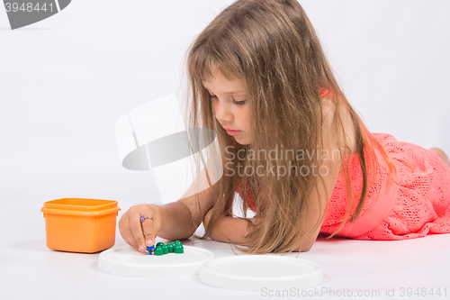 Image of Five-year girl collects mosaic lying on the floor