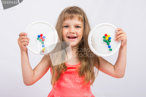 Image of Girl shows colorful flowers collected from the mosaic