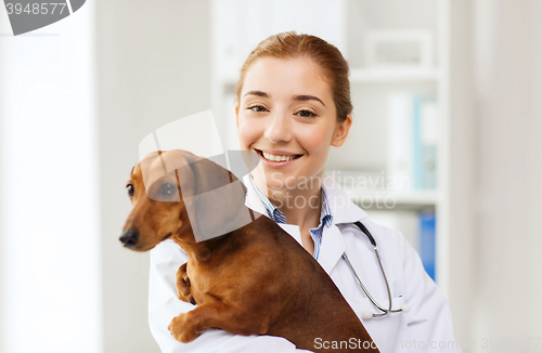 Image of happy doctor with dog at vet clinic