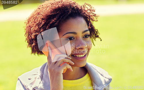 Image of happy african woman calling on smartphone outdoors