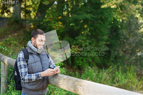 Image of happy man with backpack and smartphone outdoors