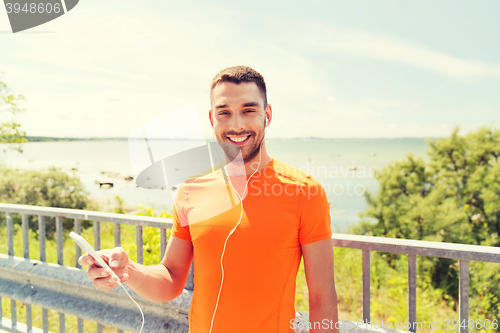 Image of smiling young man with smartphone and earphones