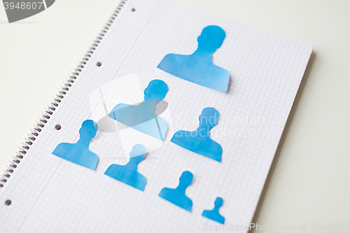 Image of close up of paper human shapes on notebook