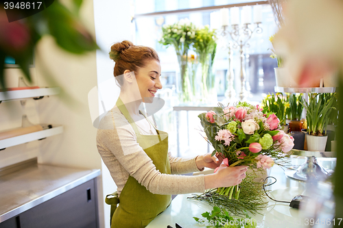 Image of smiling florist woman making bunch at flower shop