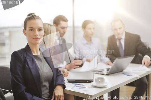 Image of businesswoman in office with team on the back