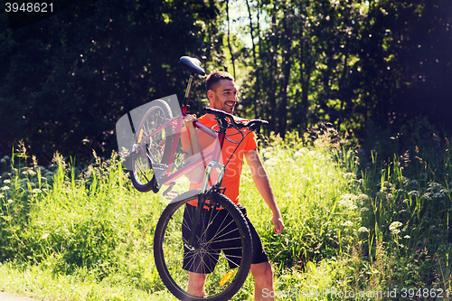 Image of happy young man riding bicycle outdoors